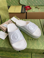 Pair of white logo slide sandals with embossed interlocking emblem on wide straps