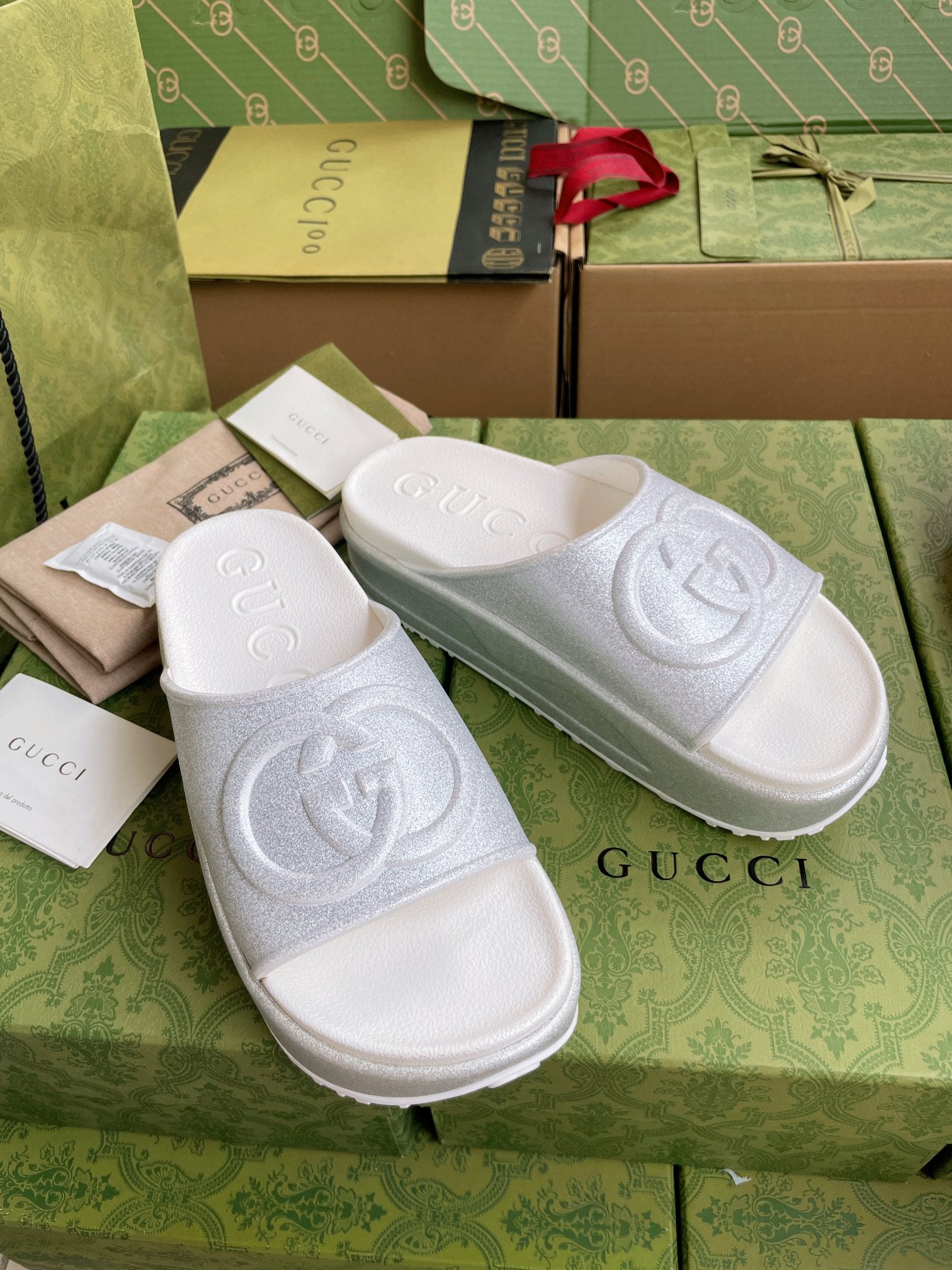 Pair of white logo slide sandals with embossed interlocking emblem on wide straps