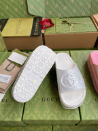 Logo slide sandals with embossed emblem; white and pink pairs on display
