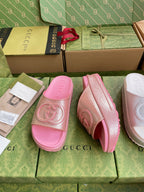 Pink logo slide sandals with embossed emblem; one shown from side angle