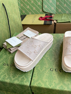 White GG logo slide sandals with embossed double straps and padded platform sole