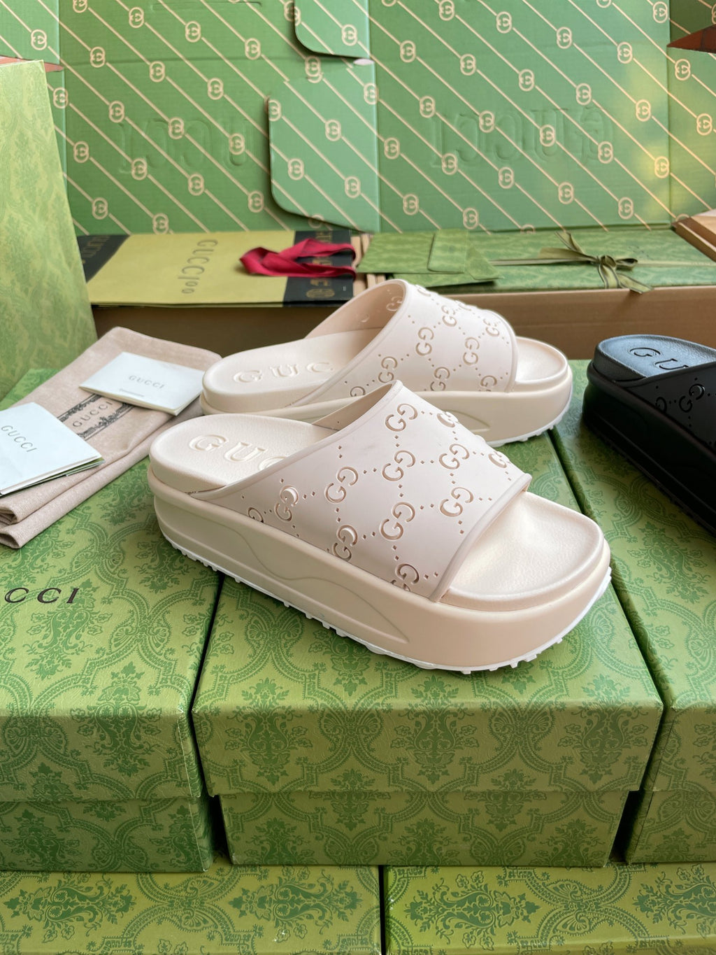 White GG logo slide sandals with embossed straps and chunky sole on shoeboxes