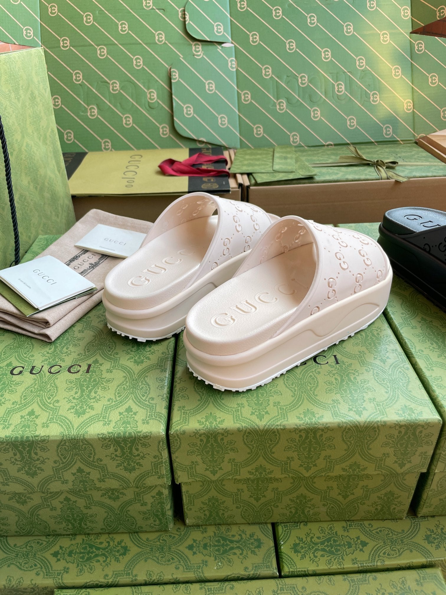 White GG logo slide sandals with embossed footbed and thick sole in a pair