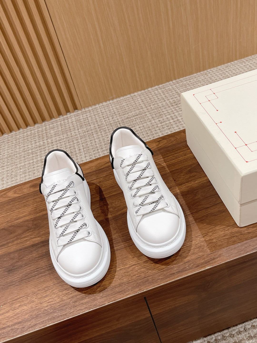 Pair of white low-top sneakers with black piping and lace-up design