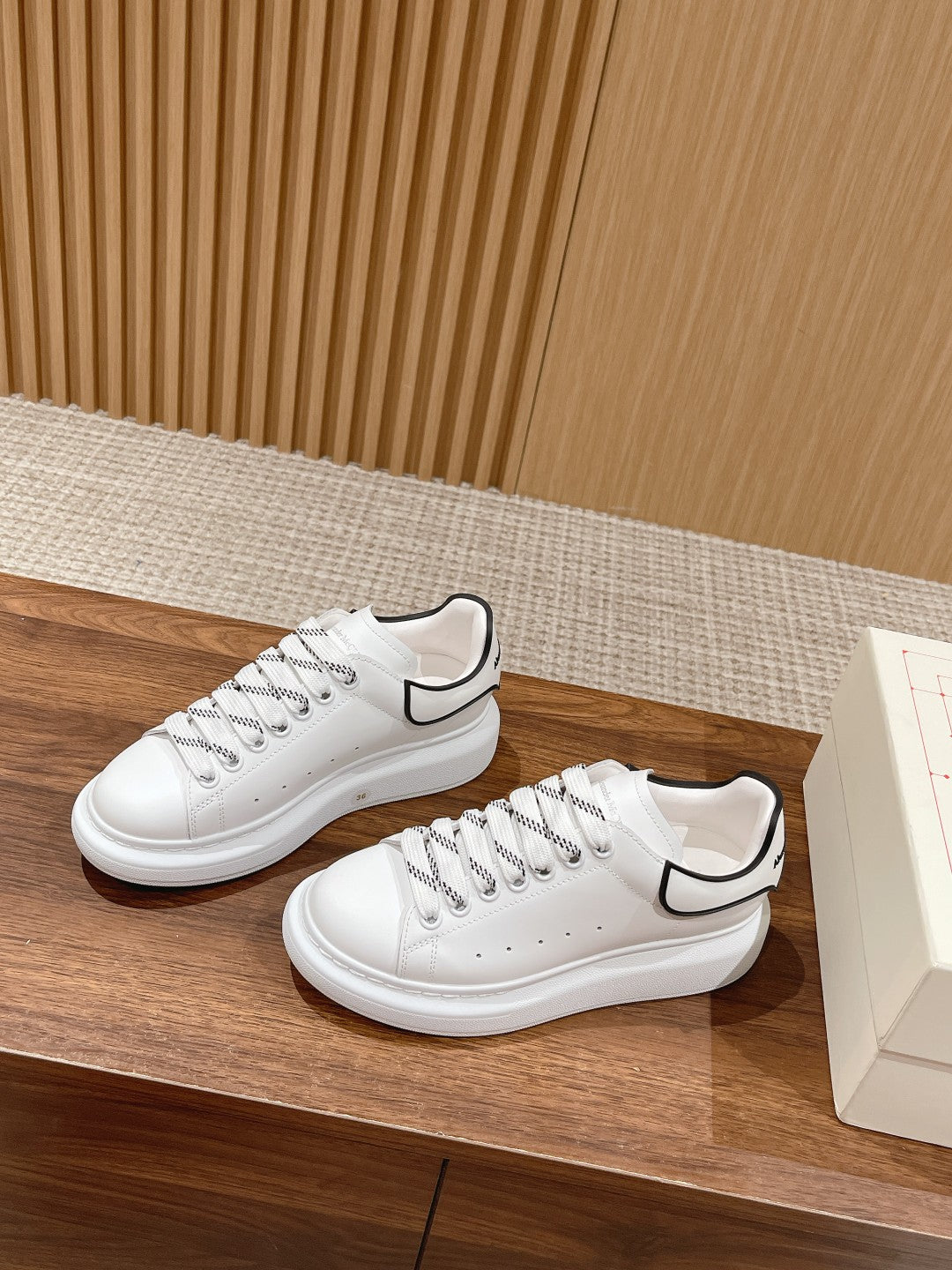 White low-top sneakers with black collar trim and lace-up construction