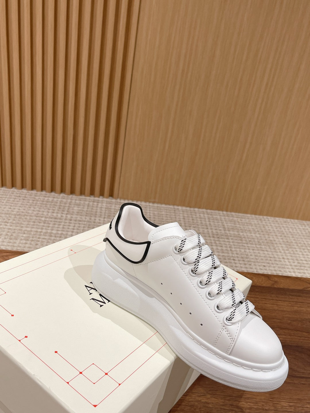 White leather sneakers with black-trim collar, lace-up, and perforated toe