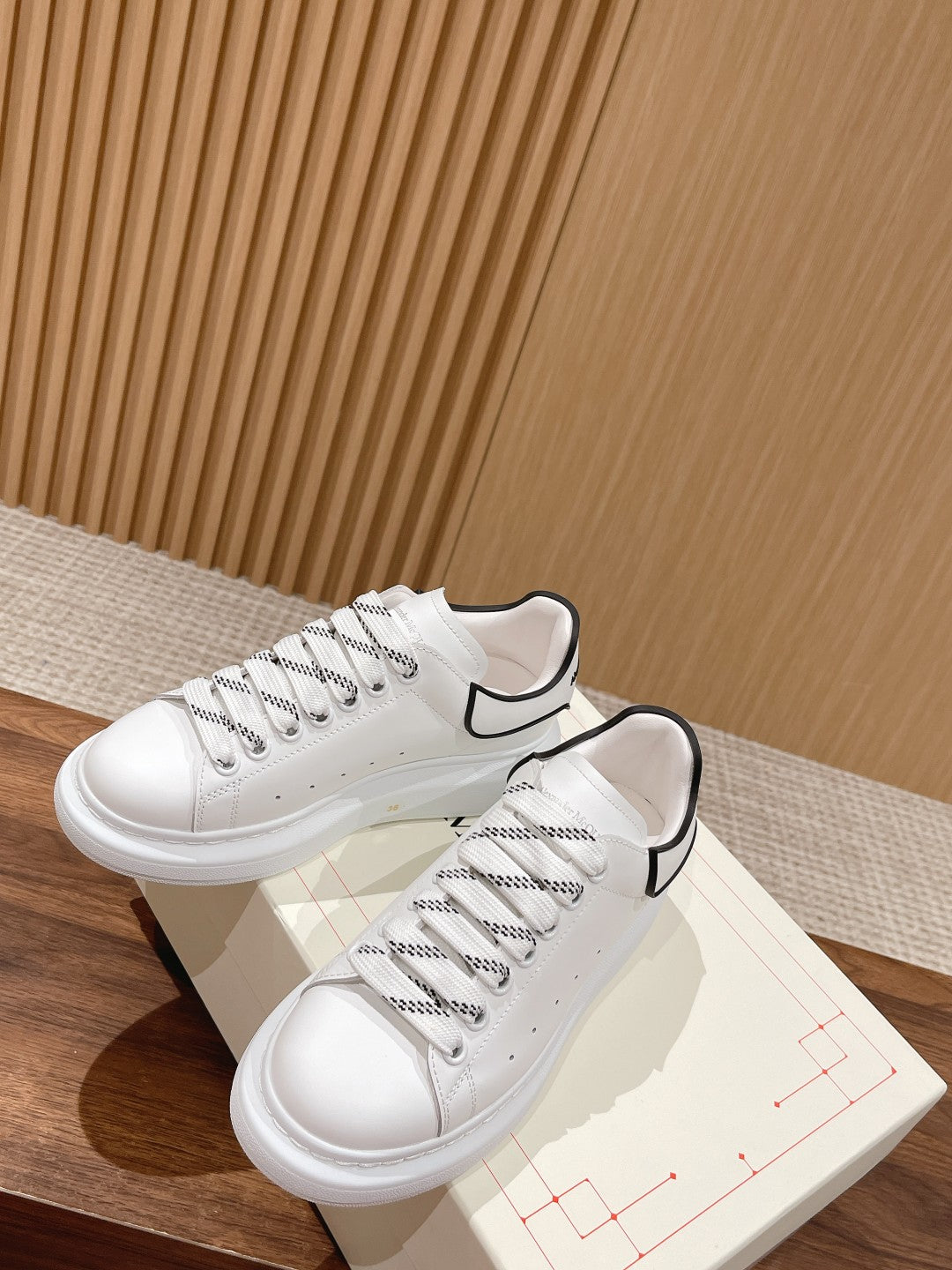 White lace-up sneakers with black collar edging and perforated toe