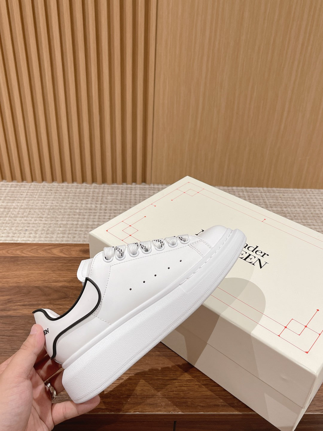 White lace-up sneakers with black heel trim and perforated toe