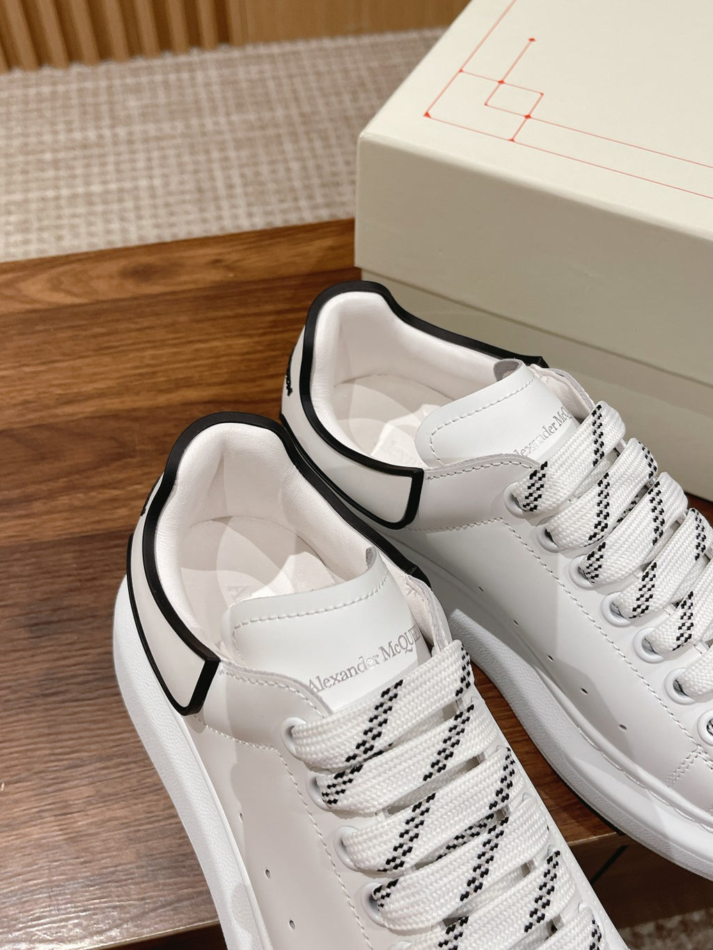 White lace-up sneakers with black collar trim, side view of stitched panels