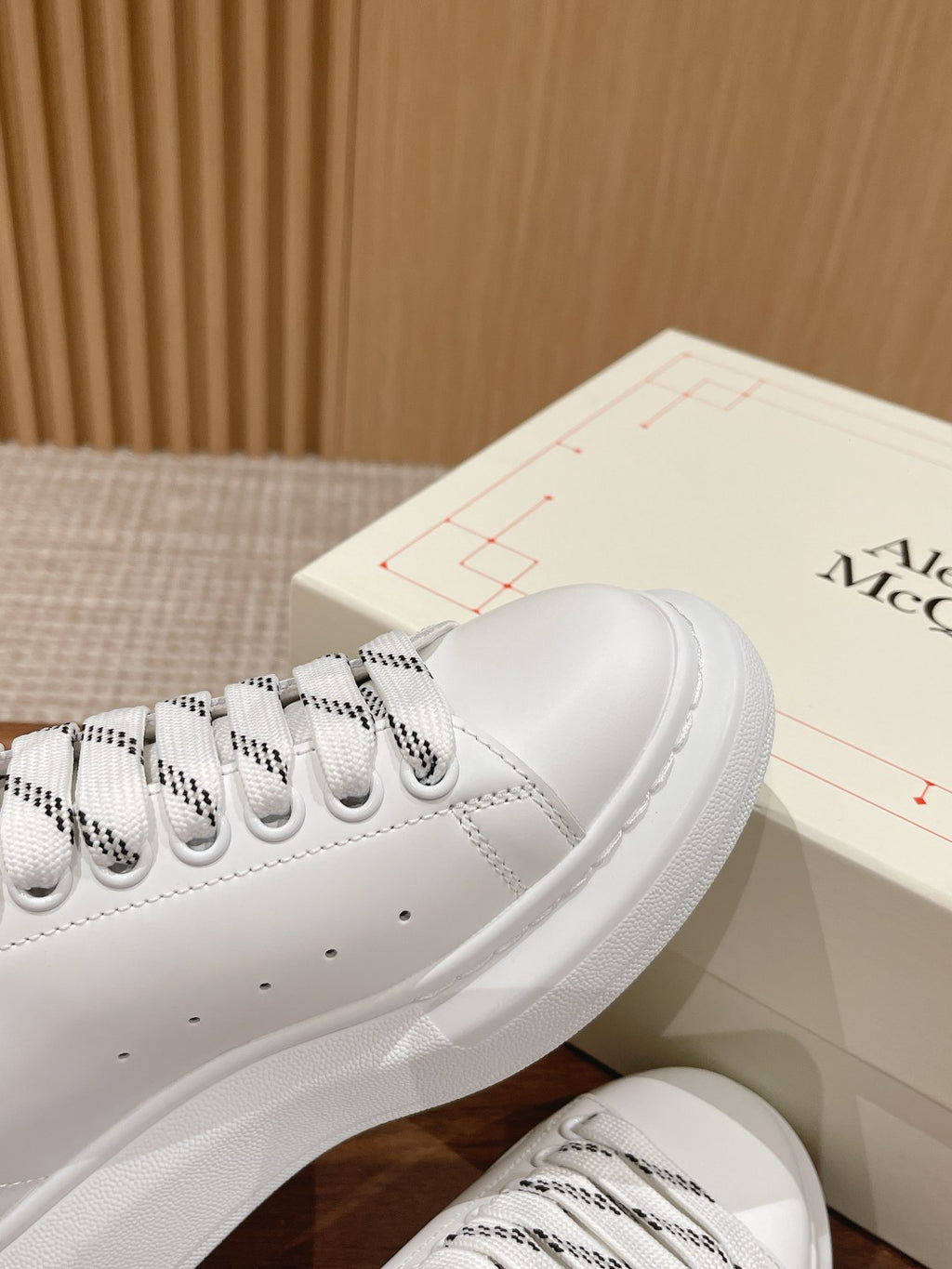 White low-top sneakers with black collar trim and patterned lace details