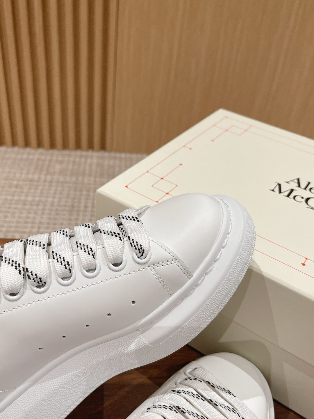 White low-top sneakers with black collar trim and patterned lace details
