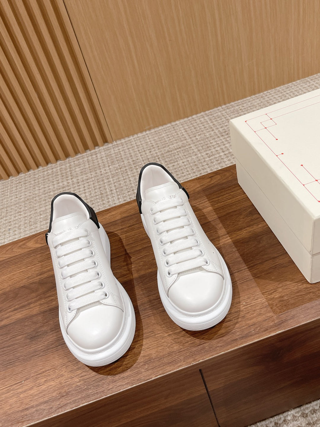 Alexander McQueen white sneakers with black side panels, laced front view