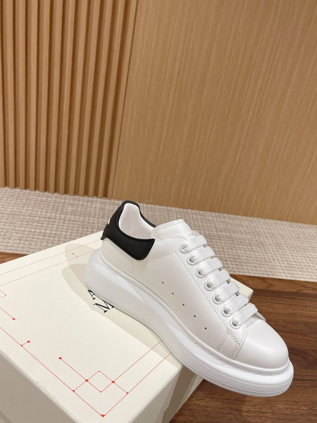 Alexander McQueen white leather sneakers with black padded collar detail, angled view