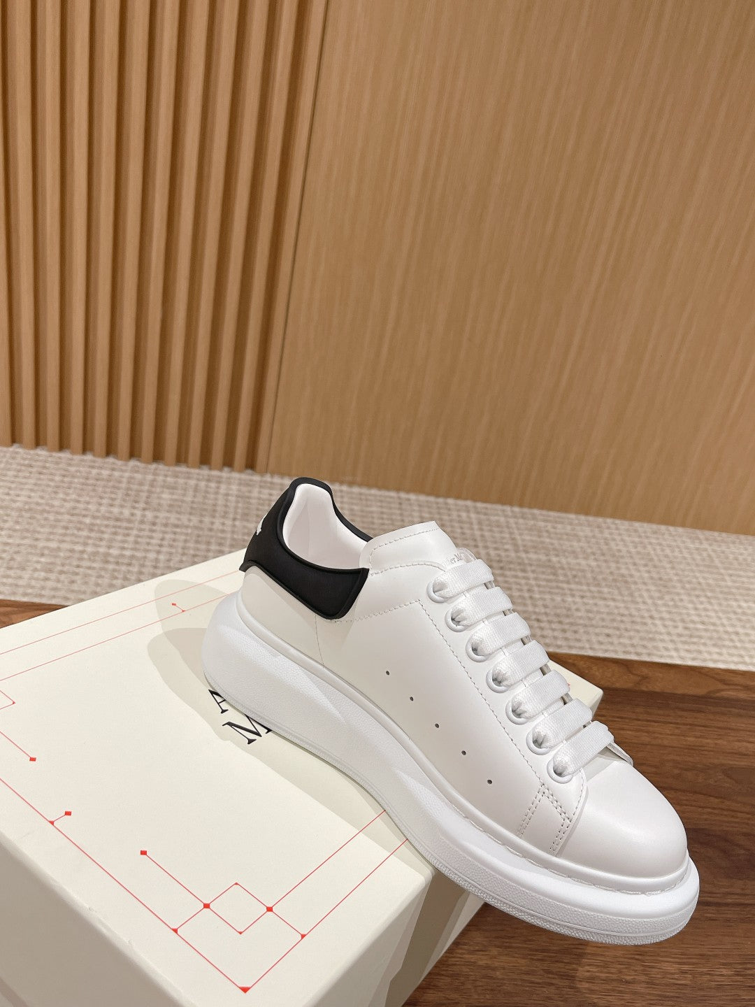 Alexander McQueen white leather sneakers with black padded collar detail, angled view