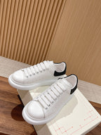 Alexander McQueen white sneakers with black heel tabs and textured side stitching, pair