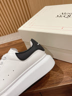 Alexander McQueen white sneakers with black slip-on heel panel, close side view