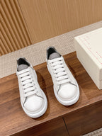Pair of white Alexander McQueen sneakers with white laces and dark inner lining
