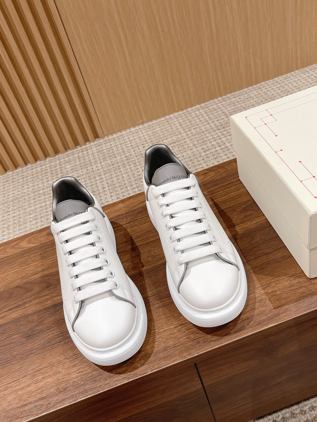 Pair of white Alexander McQueen sneakers with white laces and dark inner lining