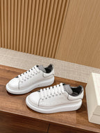 White Alexander McQueen sneakers, front angle showing perforations and laces