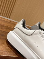 White Alexander McQueen sneakers with gray trim and thick rubber sole, side view