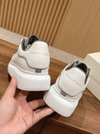 Back view of white Alexander McQueen sneakers with gray heel tabs and thick sole