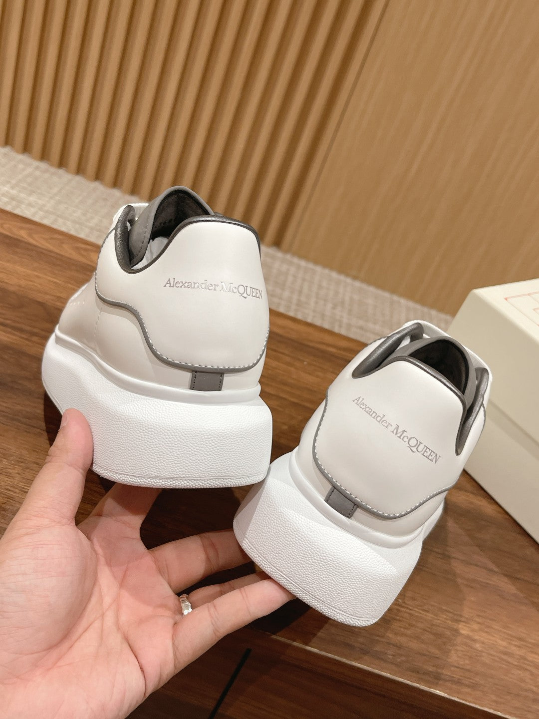 Back view of white Alexander McQueen sneakers with gray heel tabs and thick sole