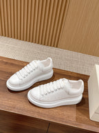 Alexander McQueen white lace-up sneakers pair on display, front and side angles