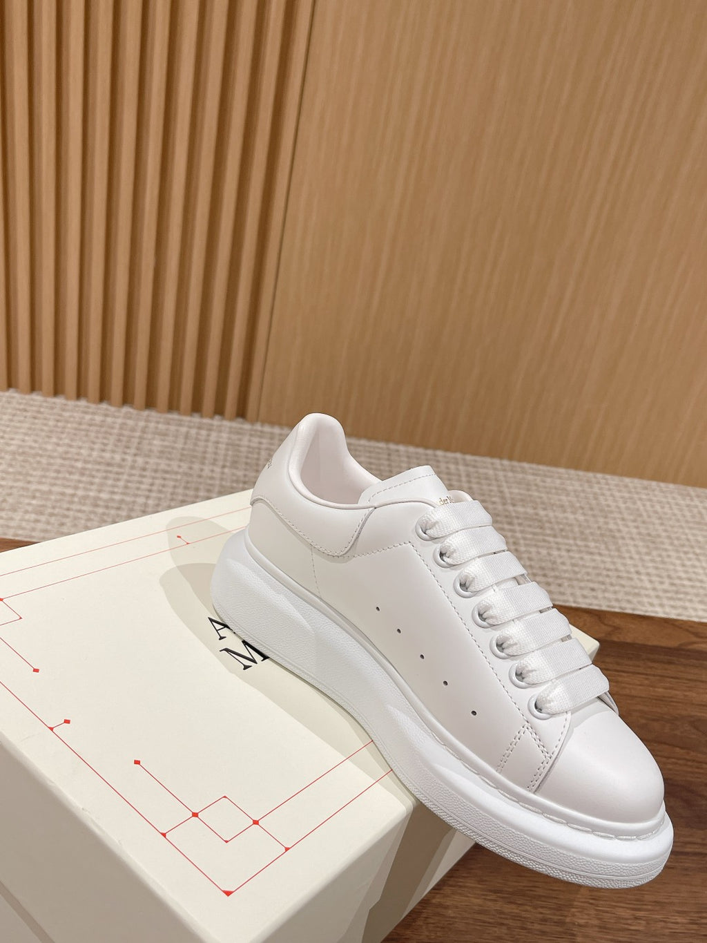 Alexander McQueen white lace-up sneakers on box, sleek leather upper