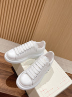 Alexander McQueen white lace-up sneakers on box, curved rubber sole
