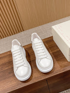 Pair of white lace-up sneakers with low-profile rubber sole