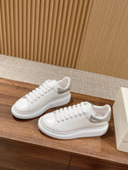 White low-top lace-up sneakers on wooden surface, side view