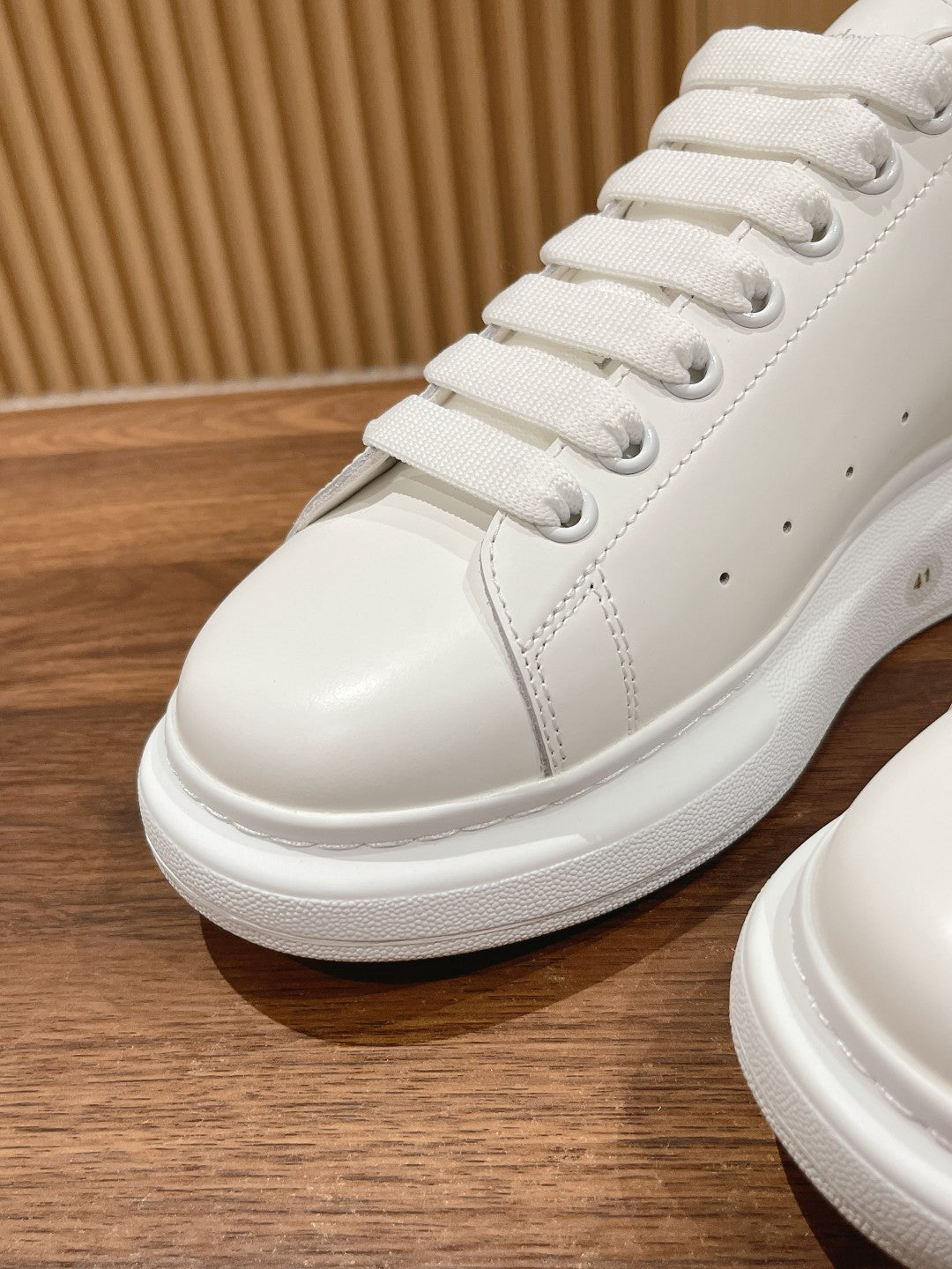 Close-up of white lace-up sneakers with thick textured rubber sole