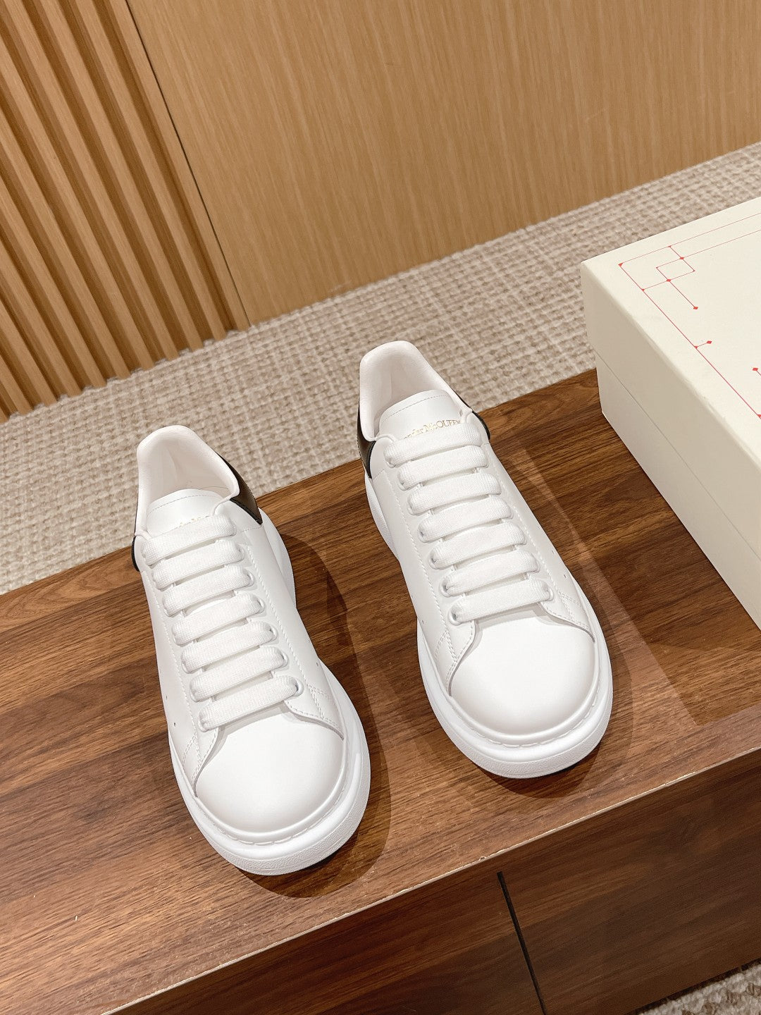 Pair of white leather lace-up sneakers with black heel accents and thick rubber sole