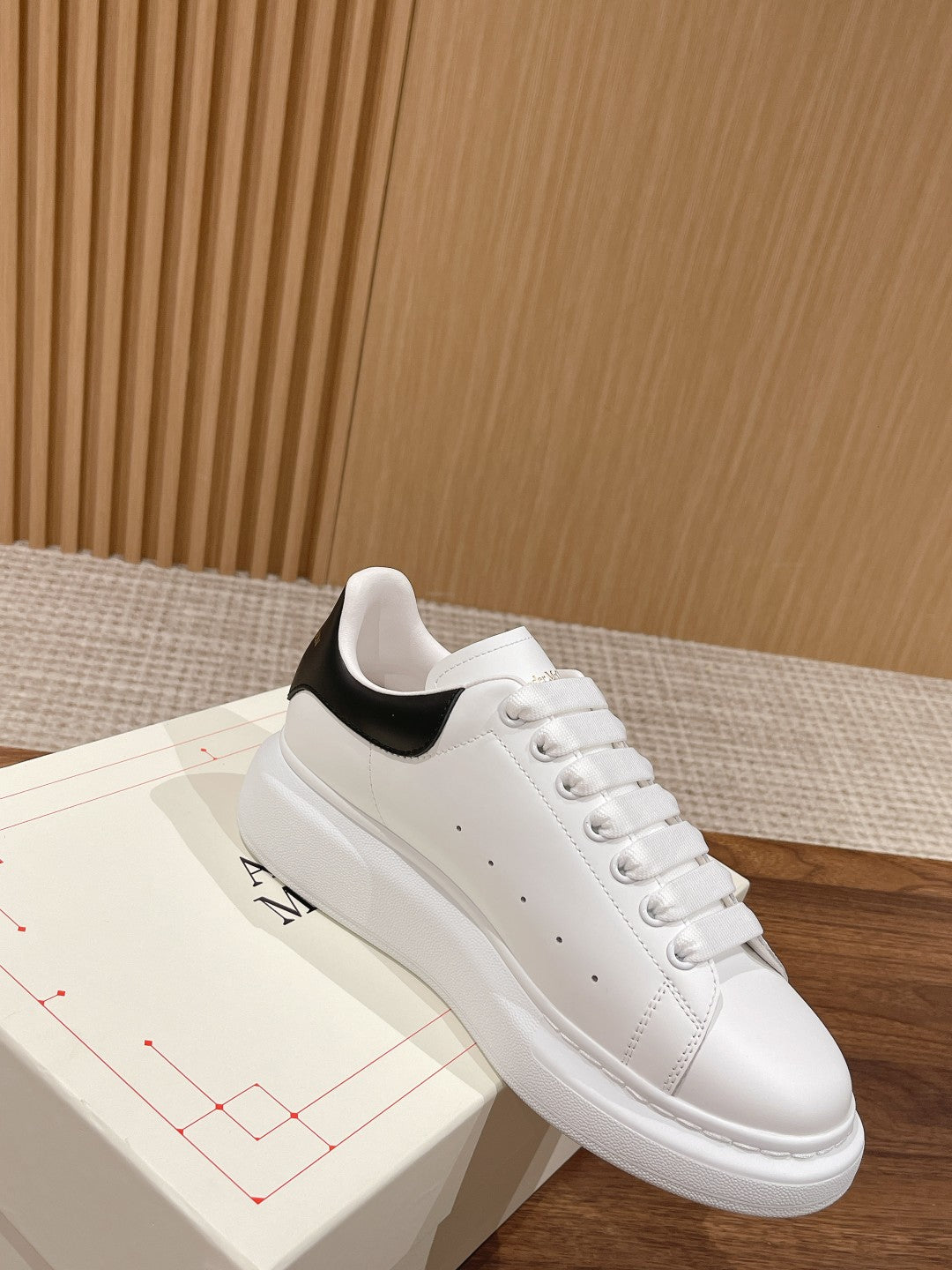 White leather sneakers with black collar trim and lace-up front, low-profile sole