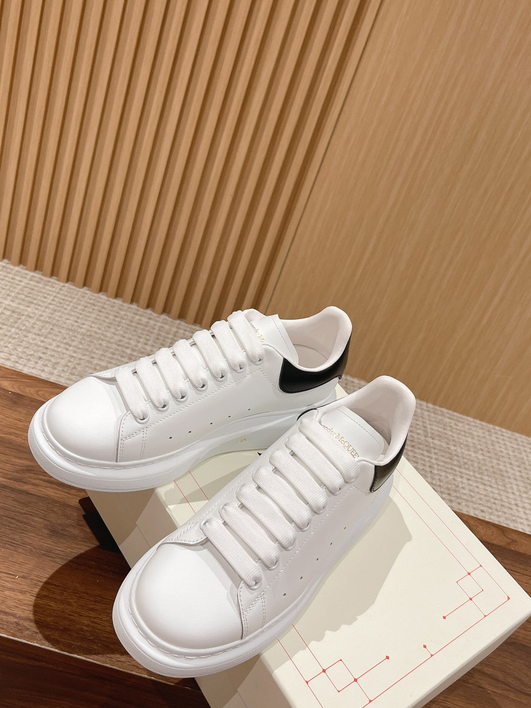 White leather low-top sneakers with black heel accents, lace-up with padded collar