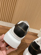 White sneakers with black heel insert showing Alexander McQueen lettering, side view