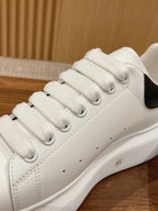 Close-up of white leather lace-up sneaker with black heel lining and textured sole