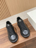 Pair of black lace-up sneakers with textured rubber toe caps and low-profile soles