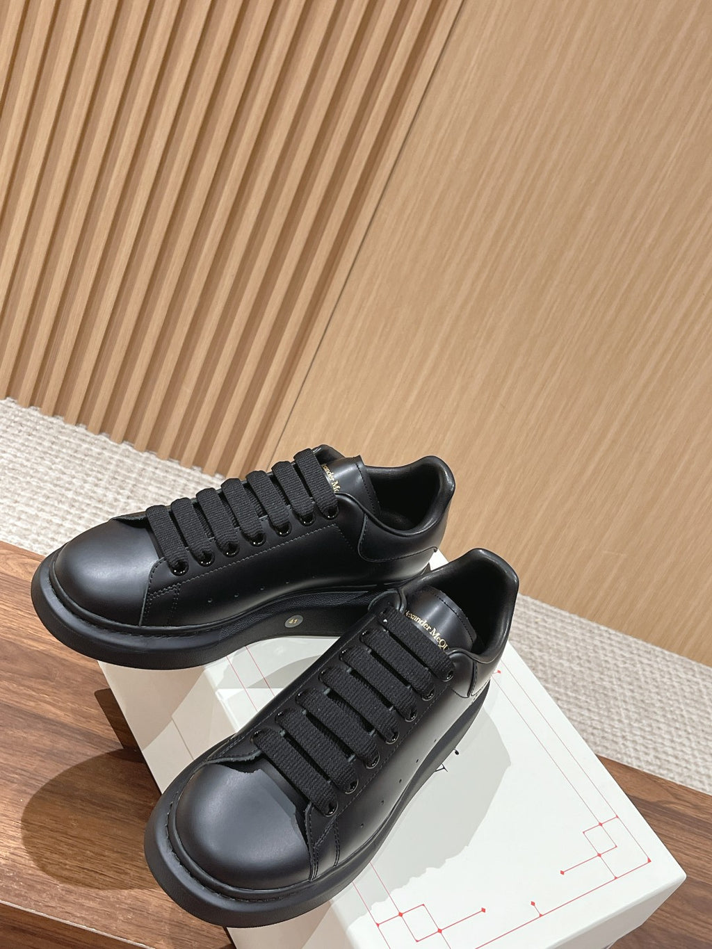 Black lace-up sneakers with thick black rubber soles and visible lace eyelets