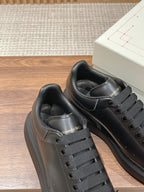 Close-up of black leather sneakers with gray laces and padded interior lining