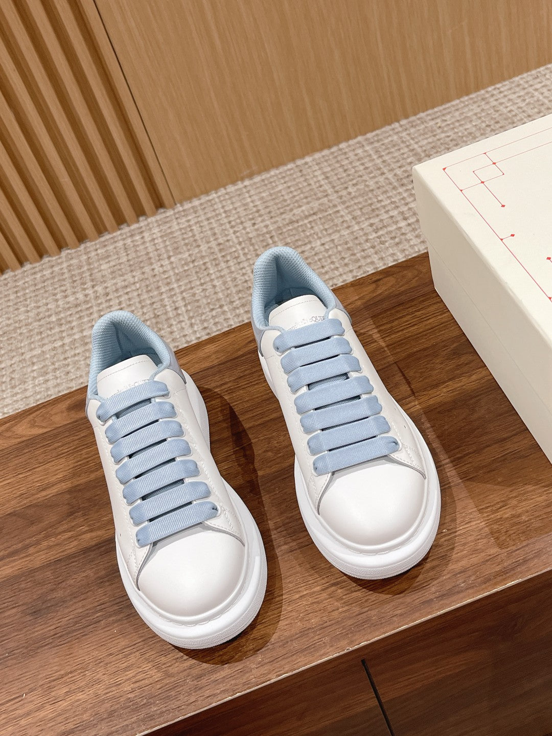 Pair of Alexander McQueen low-top sneakers with white uppers and light blue lace trim