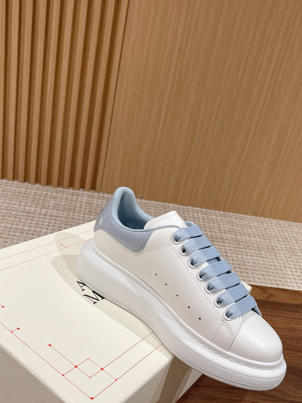 Alexander McQueen low-top sneakers, side view of white leather with light blue laces