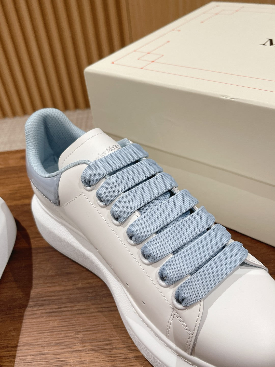 Alexander McQueen low-top sneaker, close-up of white upper with light blue lace and lining
