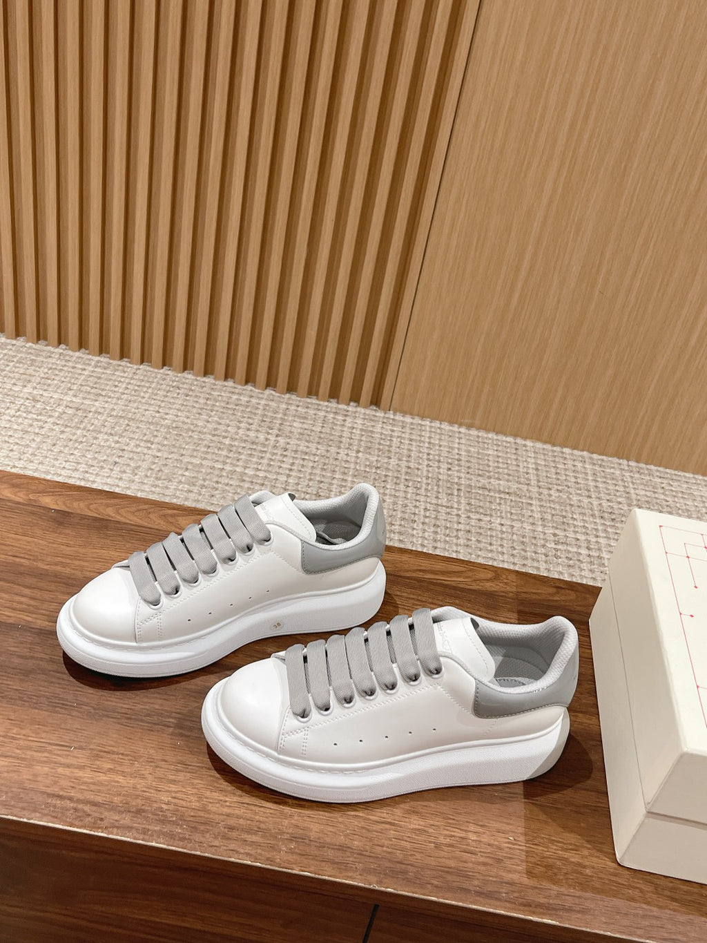 Pair of white sneakers with gray lace accents and rubber cupsole