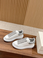 Pair of white sneakers with gray lace accents and rubber cupsole