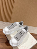 White sneakers with gray lace bands and visible lace hooks