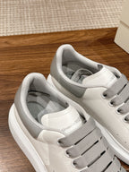 White sneakers with gray lace-up openings and textured toe stitching