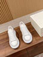 Pair of white lace-up sneakers with rounded toe and cushioned midsole