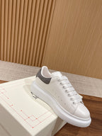 White leather low-top sneakers with gray suede heel and lace-up design
