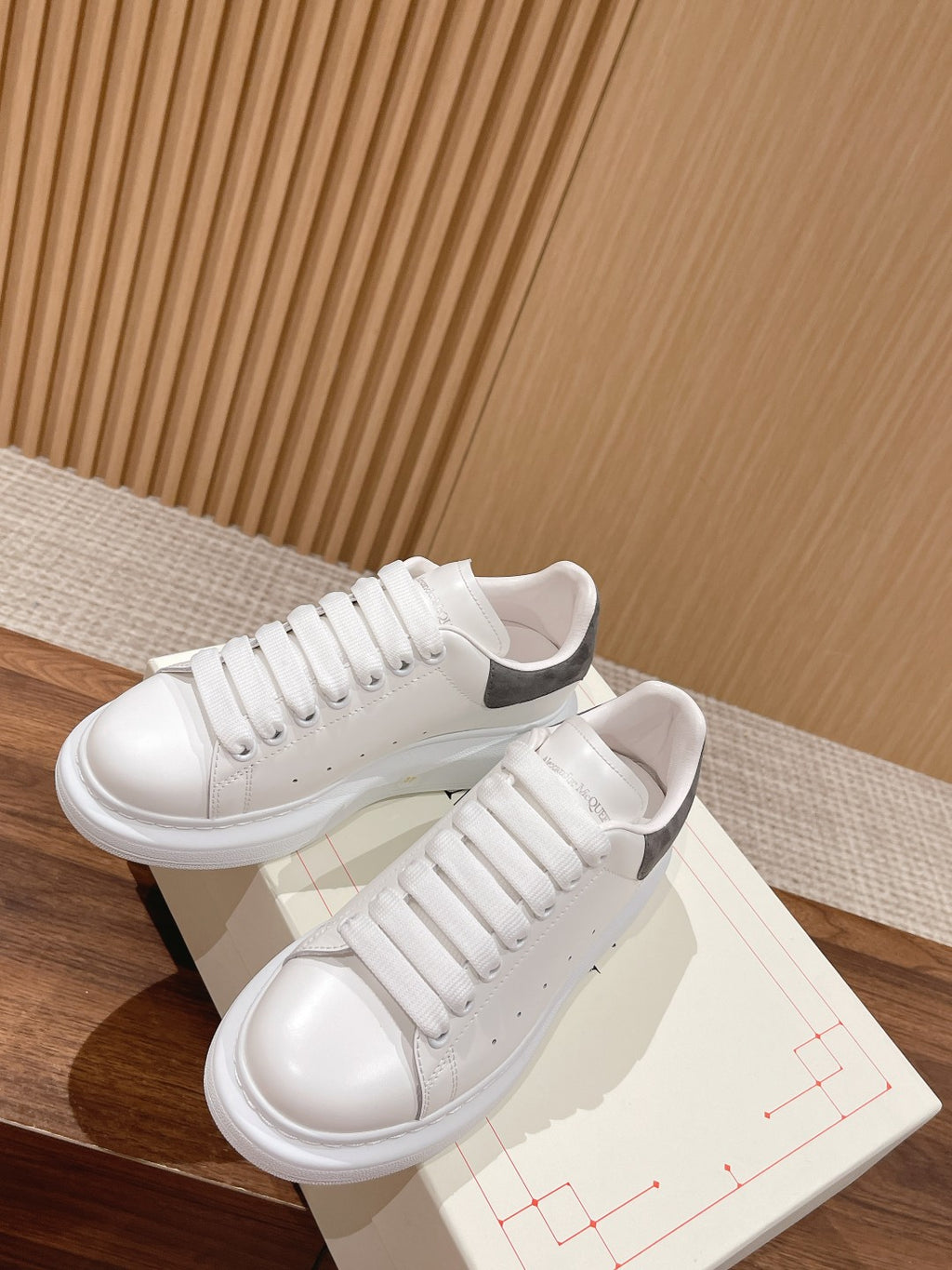 White leather lace-up sneakers with gray suede heel, on shoebox display